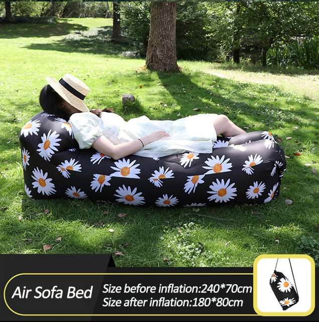 Oppblåsbar sofa i svart med blomster perfekt for camping og utendørsaktiviteter. Enkel å blåse opp og komfortabel å sitte på.